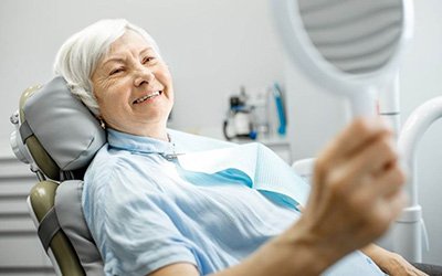 a patient checking her smile after getting dentures