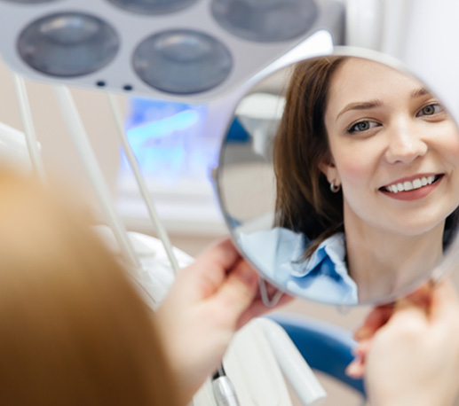 Dental patient looking at her smile in mirror