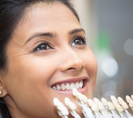 Woman's smile compared with veneer shade chart