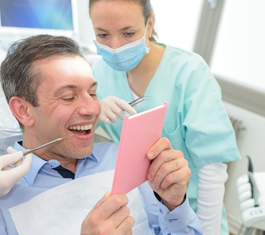 Patient looking at dental crown in the mirror at appointment