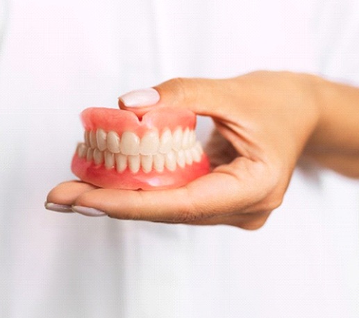 dentist holding a set of full dentures