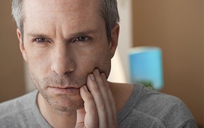 Man with toothache holding cheek