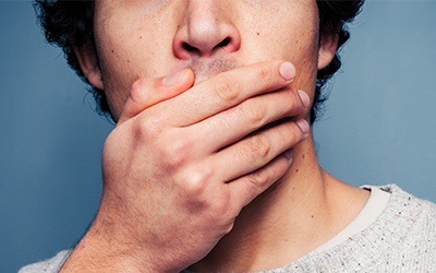 Man with lost dental filling covering mouth