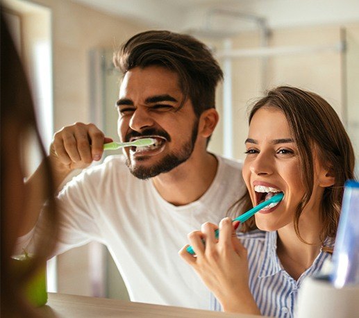 Man and woman brushing teeth to prevent dental emeregencies