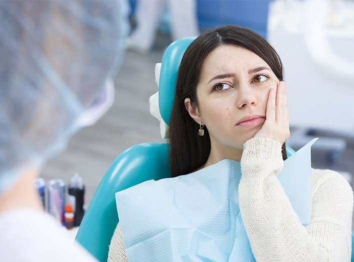 Woman in need of emergency dentistry holding jaw