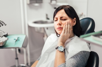 Woman in need of emergency dentistry holding jaw