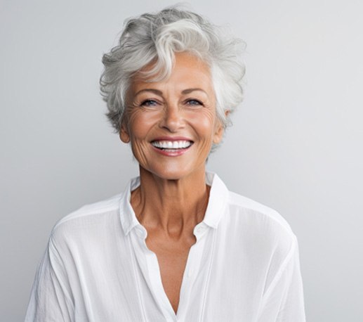 woman smiling and wearing white in front of a white background 