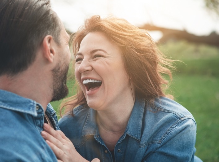 Man and woman laughing together after dental implant tooth replacement