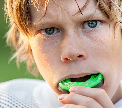 Teen boy placing athletic mouthguard