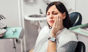 Woman in need of emergency dentistry holding jaw