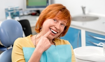 Woman pointing to smile after replacing missing teeth