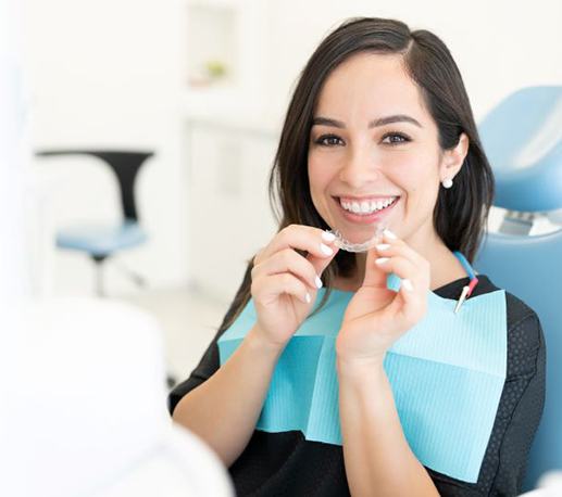 Smiling dental patient holding clear aligner
