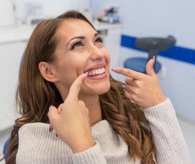 Woman pointing to smile after teeth cleaning