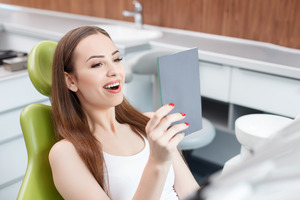 Woman looking at her smile in a handheld mirror