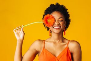 smiling woman holding a flower up to her face